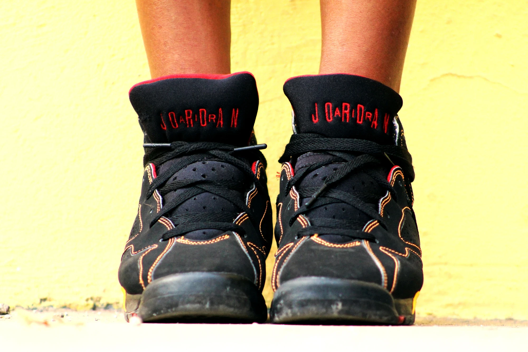 Close-up of Air Jordan sneakers against yellow wall