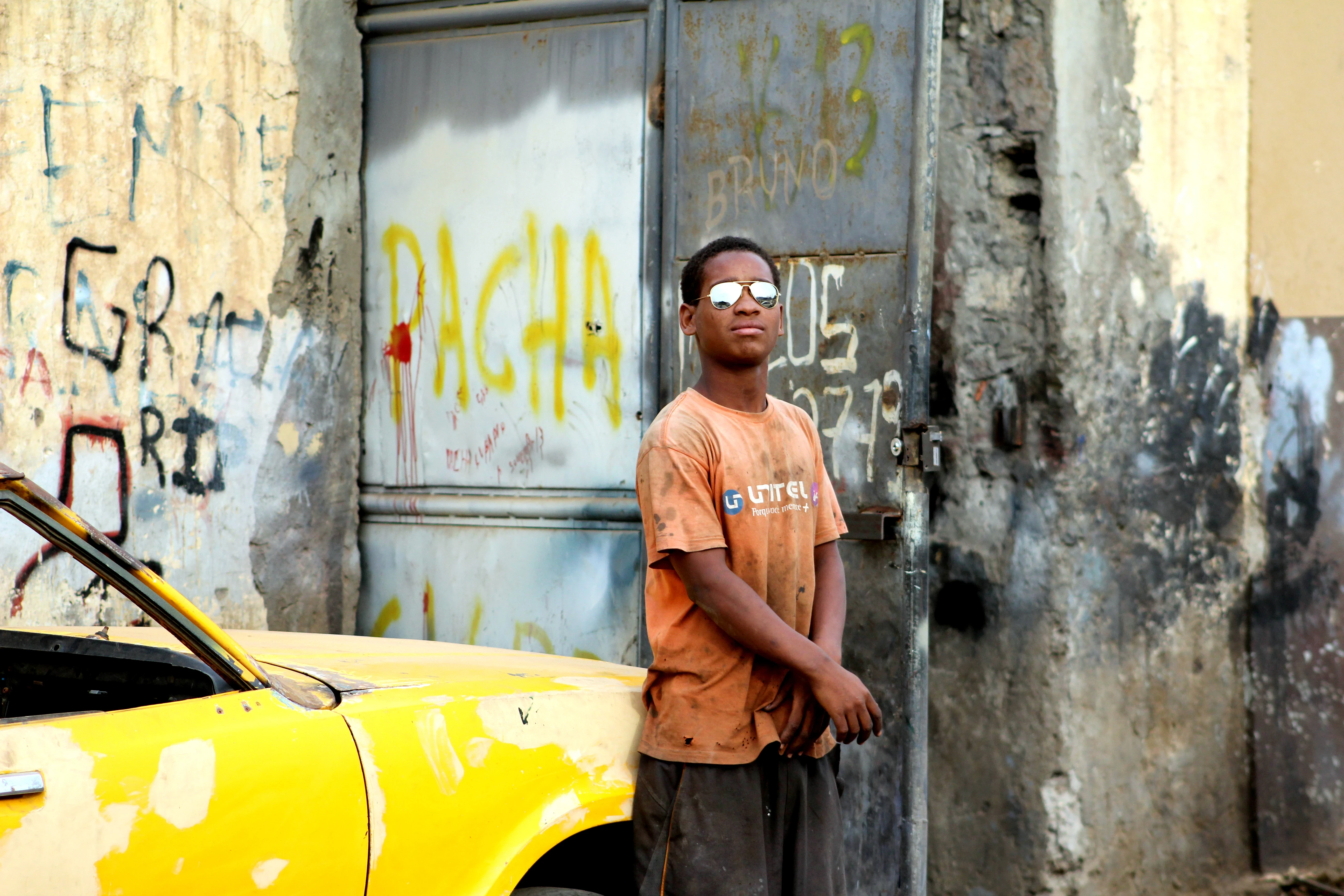 Boy with aviator sunglasses standing by a graffiti wall